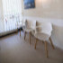Wartezimmer mit drei weißen Stühle und einem Wandbild