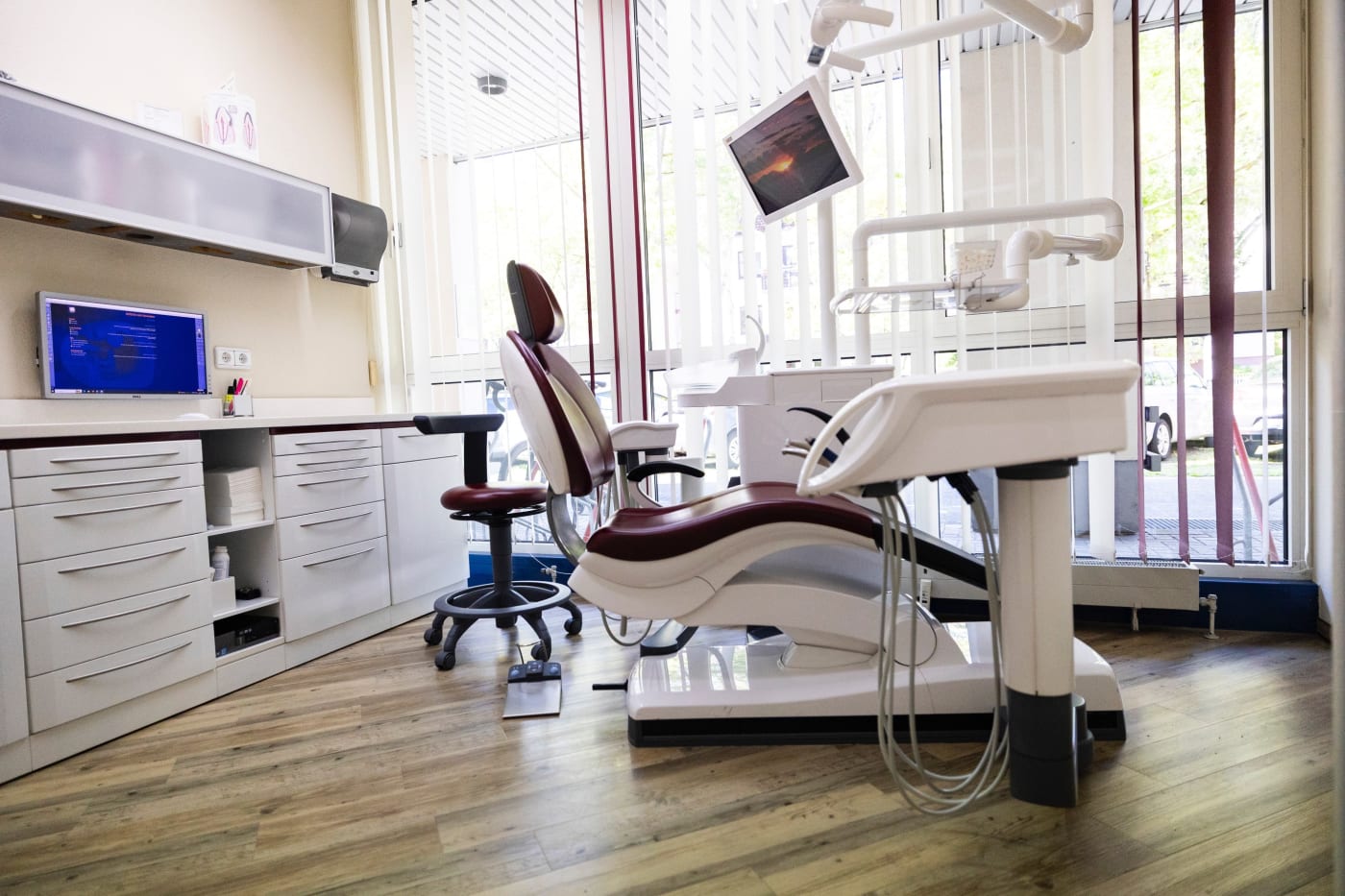 Zimmer mit rot-weißer zahnärztlicher Behandlungseinheit und weißen Schränken